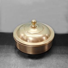 a gold covered dish sitting on top of a black countertop next to a white wall