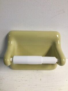 a green wall mounted toothbrush holder with a white tube on the top of it