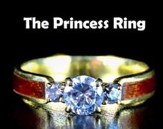 the princess ring is shown with three stones on it's sides and an orange stripe around the band