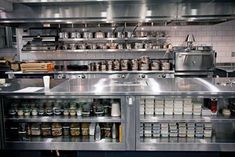 an industrial style kitchen with stainless steel counters and shelves filled with spices, condiments, and other items