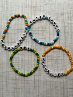 four bracelets with words written on them sitting next to each other in different colors