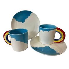 a set of three cups and saucers with clouds painted on the side, sitting next to each other