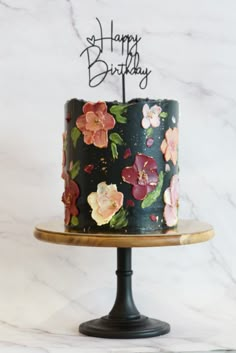 a birthday cake decorated with flowers and the words happy birthday written on it in black frosting