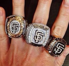 three men's rings on their fingers, one with the number 54 and the other with the word san francisco