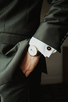 a man in a suit and white shirt is holding his watch