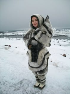 a woman standing in the snow wearing an animal suit and holding her hands up to her chest