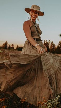 a woman wearing a hat and dress in a field