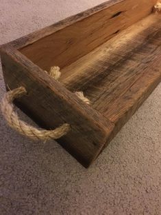 a wooden box with rope hanging from it's sides on the carpeted floor