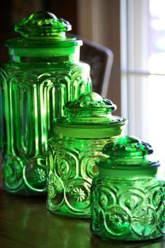 green glass jars sitting on top of a wooden table