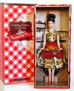 a doll in a red and white box with a turkey on the table next to it