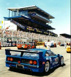 the race cars are racing down the track in front of an empty stadium full of people