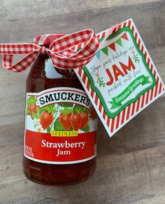 a jar of jam sitting on top of a wooden table next to a tag that says strawberry jam