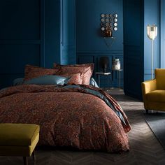 a bed in a room with blue walls and patterned comforter on top of it