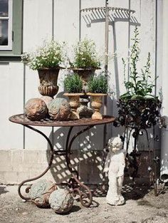 a table with potted plants on it next to a white building and a small teddy bear