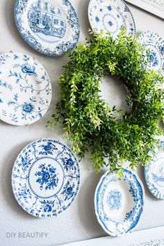 blue and white plates are hung on the wall with a wreath in front of them