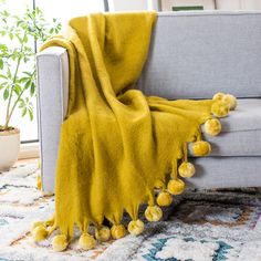 a couch with a yellow blanket and pom - poms on it