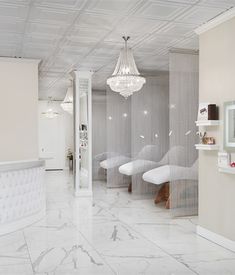 the interior of a salon with white furniture and chandelier