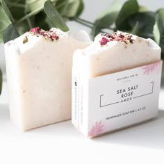 two soap bars sitting next to each other on top of a white table with green leaves