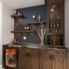 a kitchen with wooden cabinets and shelves filled with bottles, wine glasses and other items