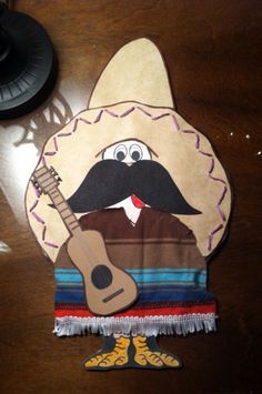 a paper cutout of a man with a mustache and hat holding a guitar on top of a wooden table