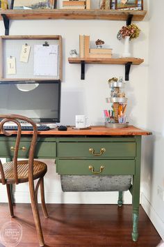 a desk with a computer on top of it next to a chair and bookshelves