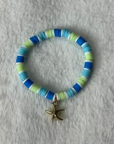 Heishi/clay beaded bracelet: ocean starfish charm -good quality -very stretchy -one size: about 6.5 inches (can stretch to around 8 inches)  This bracelet contains a gold starfish charm, and blue, white, and light green clay/heishi beads upon good quality and stretchy string.  This bracelet comes in one size (measures about 6.5 inches) and is meant to fit people with small and medium size wrists. If you have a larger wrist than about 8 inches, then send me a message to get a custom bracelet. Turquoise Clay Bracelet, Clay Bead Bracelet Ideas Blue And Green, Blue And Green Clay Bead Bracelet, Hawaii Clay Bead Bracelets, Green Heishi Beads Jewelry For Beach, Green Heishi Beads Bracelets For Beach, Green Beaded Bracelets With Letter Beads For Vacation, Green Letter Beads Bracelets For Vacation, Green Clay Bracelet