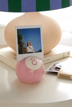 a pink ball sitting on top of a white table next to a book and lamp