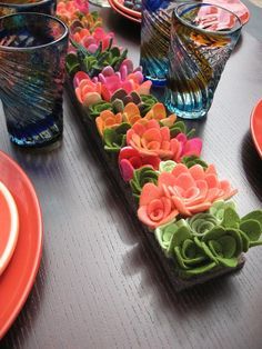 the table is set with colorful flowers and place settings for each individual to sit on