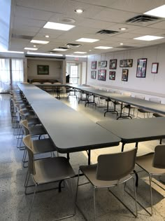 an empty conference room with long tables and chairs in front of the table are pictures on the wall