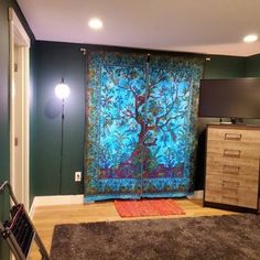 a living room with green walls and a blue tree tapestry on the wall behind it