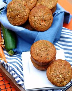 carrot muffins are sitting on a plate next to a blue towel and some vegetables