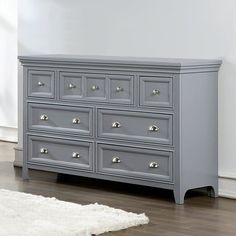 a large gray dresser sitting on top of a hard wood floor next to a white rug