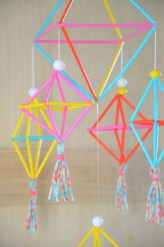 four colorful objects hanging from strings in the shape of an origami structure with tassels