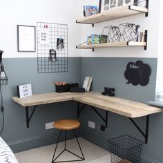 a corner desk in the corner of a room with two shelves above it and a chair at one end