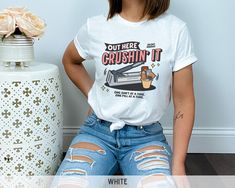 a woman sitting on the floor next to a vase with flowers in it and wearing a white shirt that says, out here crushin't