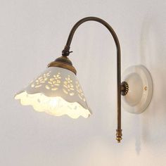 a light that is on the wall next to a white wall mounted lamp with a glass shade