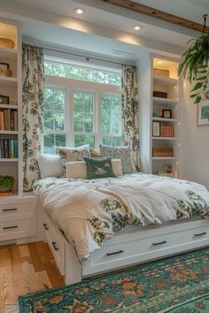 a bed sitting under a window next to a green rug on top of a hard wood floor