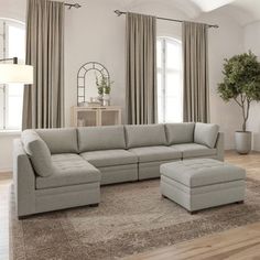 a living room with a large sectional couch and ottoman in it's center area