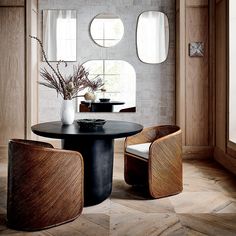 a black table with two chairs and a vase on it in front of three round windows