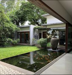 a large vase sitting in the middle of a garden next to a pond with koi fish