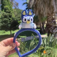 a hand holding up a crocheted headband with an animal on it