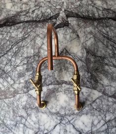 two metal handles on a marble surface with gold colored fittings and hooks attached to them