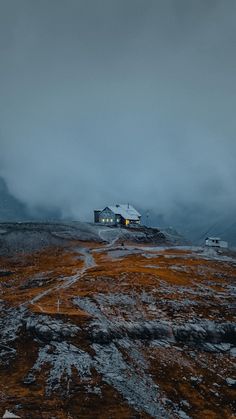 a house on top of a hill in the middle of winter with snow and fog