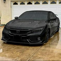 a black sports car parked in front of a garage door with water on the hood