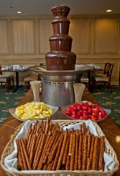 a chocolate fountain with strawberries, strawberries, and other snacks on the table