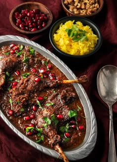 meat with pomegranates and mashed potatoes on a plate next to it