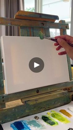 a person is painting on an easel with watercolors