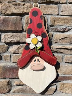 a wooden sign with a ladybug hat and flower on it's head