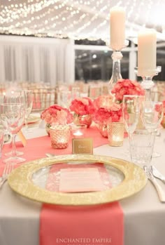 the table is set with pink and white flowers, silverware, candles, and napkins