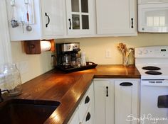 a kitchen with white cabinets and wood counter tops